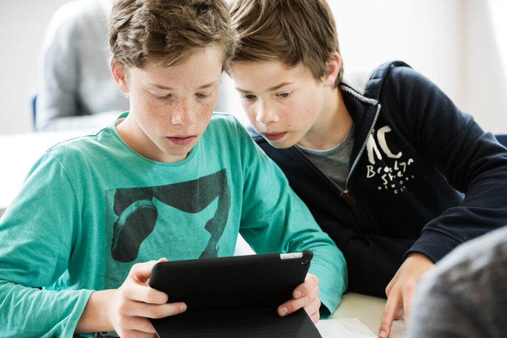 Zwei Jugendliche schauen ein Tablet an